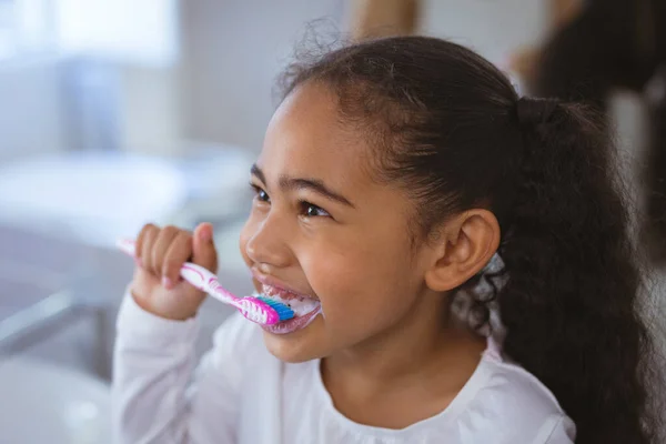 Linda Chica Biracial Cepillándose Los Dientes Mientras Mira Hacia Otro —  Fotos de Stock