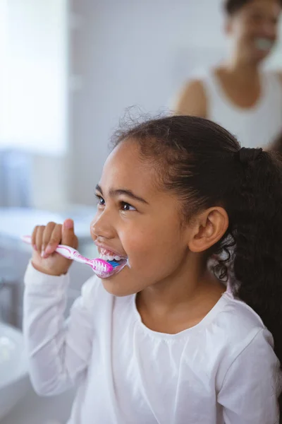 Wielorasowa Dziewczyna Myjąca Zęby Odwracając Wzrok Ojca Tle Bez Zmian — Zdjęcie stockowe