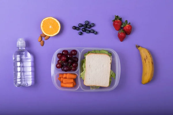 直接上方拍摄的健康食品和松饼盒由紫色背景的水瓶 复制空间 食物及健康饮食概念 — 图库照片