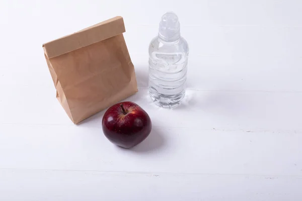 高角度的苹果和纸午餐袋 水瓶白色背景 健康食品 饮料和包装好的午餐 — 图库照片