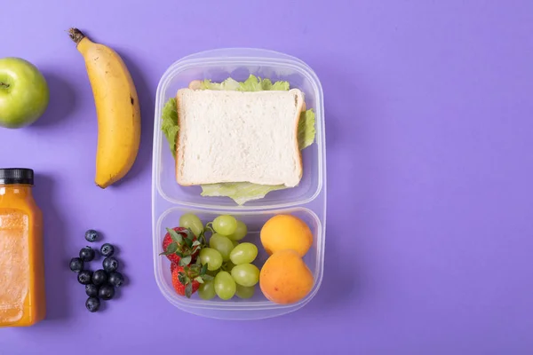 就在上面的照片水果和果汁瓶子三明治在松饼盒紫色背景 采购产品未经改动 复制空间 健康食品 水果和包装午餐 — 图库照片