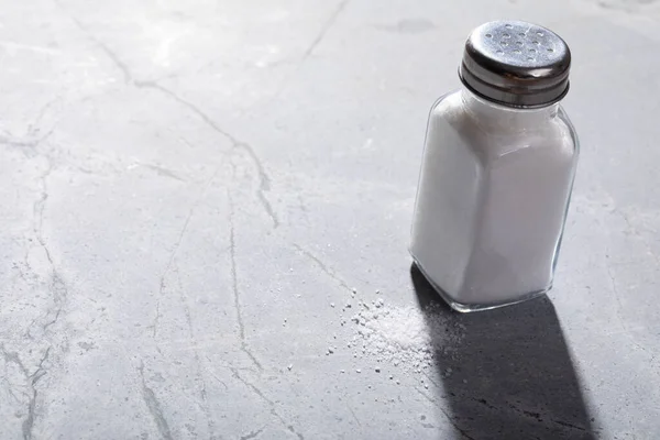 テーブルの塩のシェーカーに落ちる光の高い角度のビュー 変わることのない食材光影岩塩調味料 — ストック写真