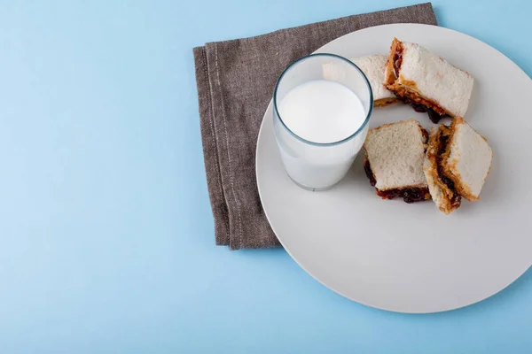 ピーナッツバターとゼリーサンドイッチのスライスは コピースペースとテーブルの上にプレートにミルクグラスで提供しています 変更なしピーナッツバターとゼリーサンドイッチナプキン健康的な食事と朝食 — ストック写真