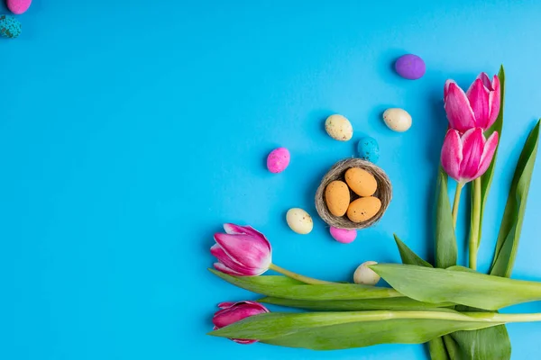 Přímo Nad Záběrem Velikonočních Bonbónů Malém Hnízdě Růžovými Tulipány Modrém — Stock fotografie