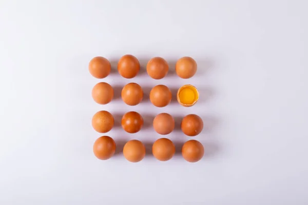 テーブルの上に正方形に配置された1つの壊れた卵と茶色の卵のショットの真上に 変わらない健康食品生食有機タンパク生卵黄身静物 — ストック写真