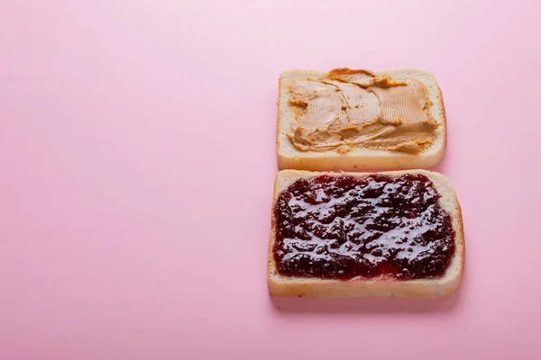 Erdnussbutter Und Marmelade Auf Brotscheiben Über Rosa Hintergrund Mit Kopierraum — Stockfoto