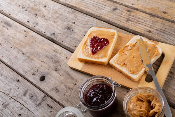 オープンフェイスのピーナッツバターとゼリーサンドイッチの高い角度のビューは テーブルの瓶でボードを提供しています 変更なしピーナッツバターとゼリーサンドイッチ健康食品テーブルナイフ準備と朝食 — ストック写真