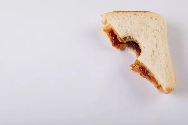 Close-up of missing bite on peanut butter and jelly sandwich over white background with copy space. unaltered, peanut butter and jelly sandwich, healthy food, copy space, bread and breakfast.