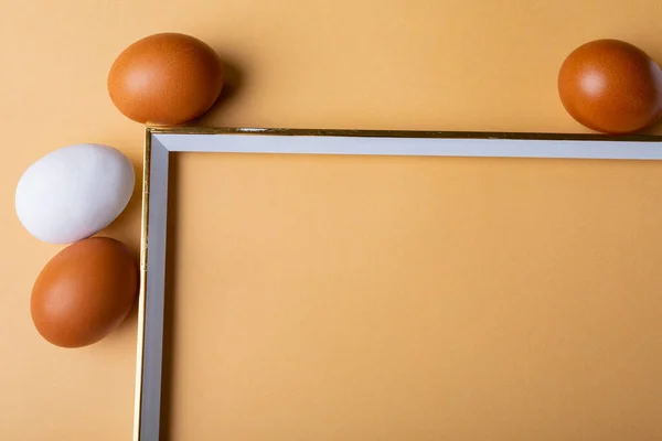 Turuncu Arka Plandaki Boş Çerçevenin Etrafında Kahverengi Beyaz Paskalya Yumurtalarının — Stok fotoğraf