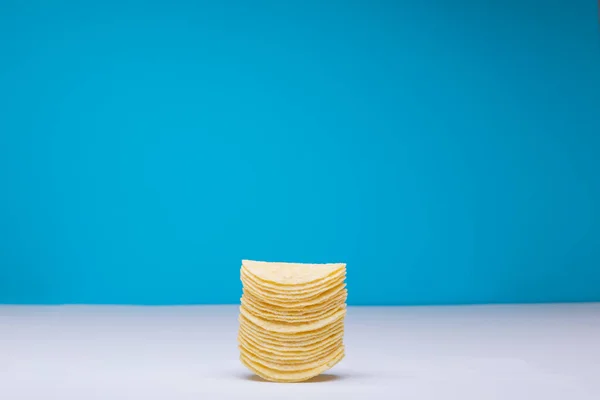 コピースペースと青の背景にテーブルの上にジャガイモチップのスタック 変化のない不健康な食べ物スナックコピースペース塩辛いスナック — ストック写真