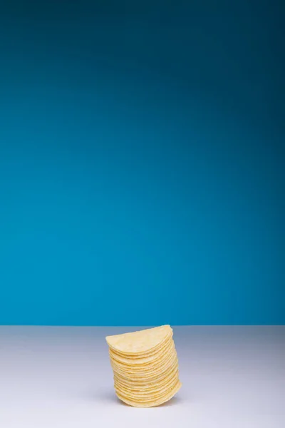 コピースペースと青の背景にテーブルの上にジャガイモチップを積層 変化のない不健康な食べ物スナックコピースペース塩辛いスナック — ストック写真