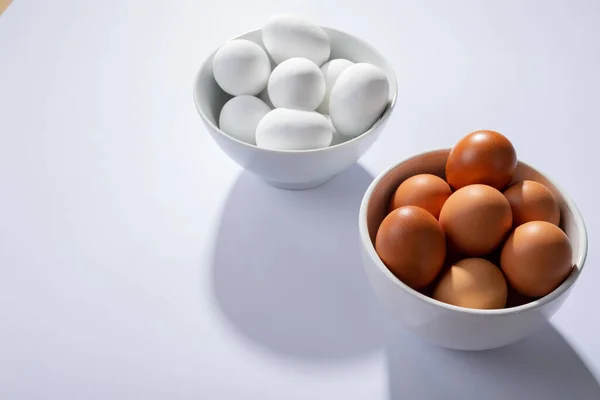 Vista Ángulo Alto Huevos Blancos Marrones Cuencos Sobre Mesa Con —  Fotos de Stock