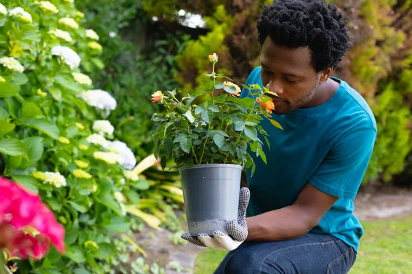 Hombre Afroamericano Que Usa Guantes Jardinería Oliendo Flores Mientras Trabaja — Foto de Stock