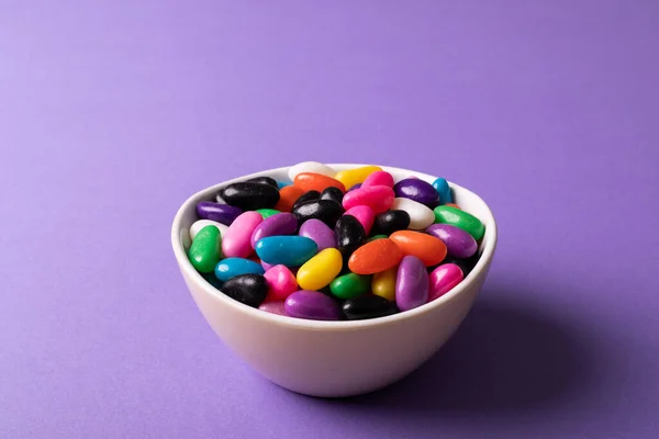 多色糖果在紫色背景的白色碗中与复制空间的特写 未经更改的甜食及不健康饮食概念 — 图库照片