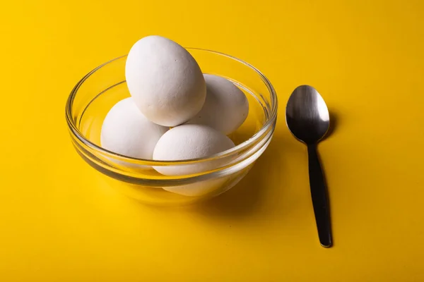 黄色の背景にスプーンでガラスボウルに新鮮な白い卵の高い角度のクローズアップ 変化のない 食べ物 健康的な食事のコンセプト — ストック写真