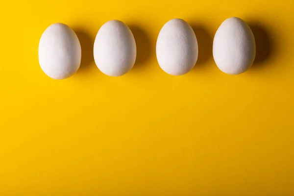 黄色の背景にコピースペースで並んで配置された新鮮な白い卵のオーバーヘッドビュー 変化のない 食べ物 健康的な食事のコンセプト — ストック写真