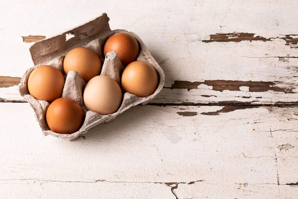 Beyaz Ahşap Masadaki Karton Kahverengi Yumurtaların Yüksek Açılı Görüntüsü Değiştirilmemiş — Stok fotoğraf