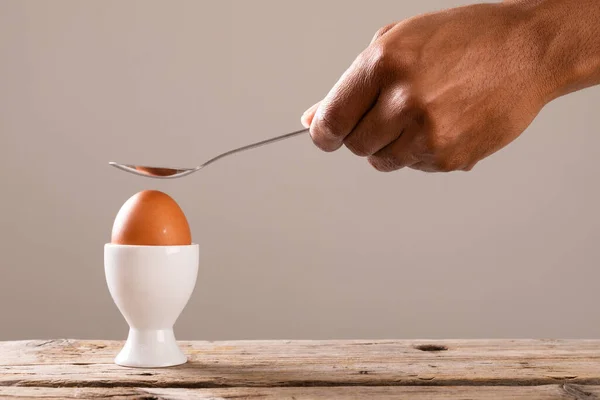 テーブルの上のカップにゆで卵の上にスプーンを保持している作物の手 変化のない食品健康的な食生活有機的な概念 — ストック写真
