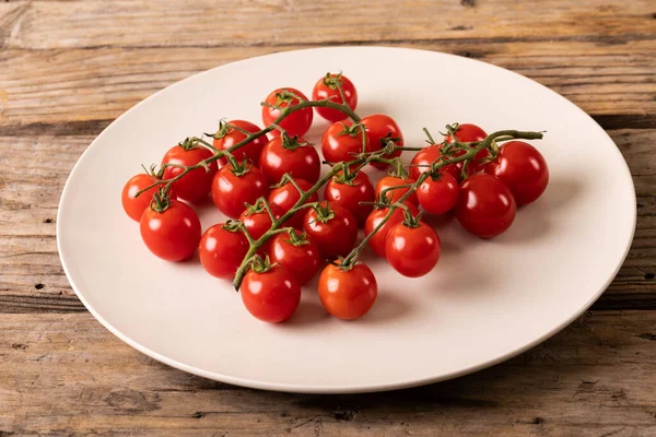 木製のテーブルの上に白いプレートに新鮮な赤チェリートマトの高い角度ビュー 変化のない有機食品や健康的な食事の概念は — ストック写真