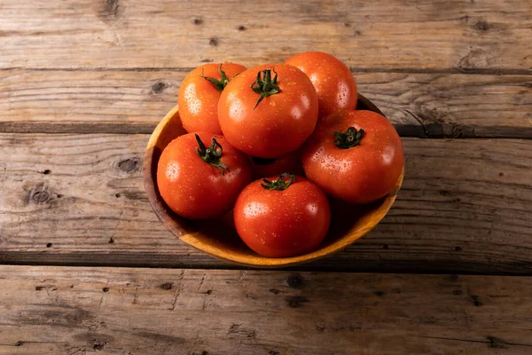 木製のテーブルの上にボウルに水滴と新鮮な赤いトマトの高角度ビュー 変化のない有機食品や健康的な食事の概念は — ストック写真