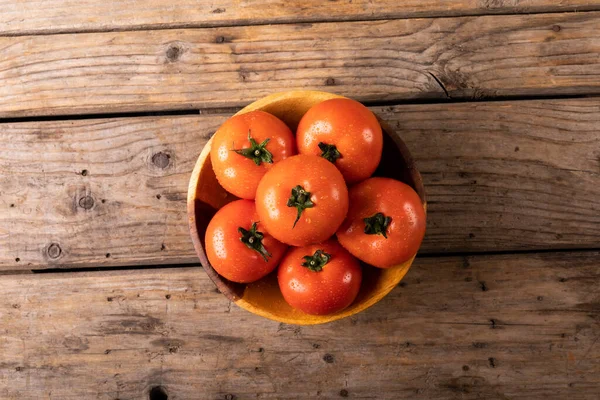 木製のテーブルの上に皿の中の新鮮な赤いトマトに水のオーバーヘッドビューが低下します 変化のない有機食品や健康的な食事の概念は — ストック写真