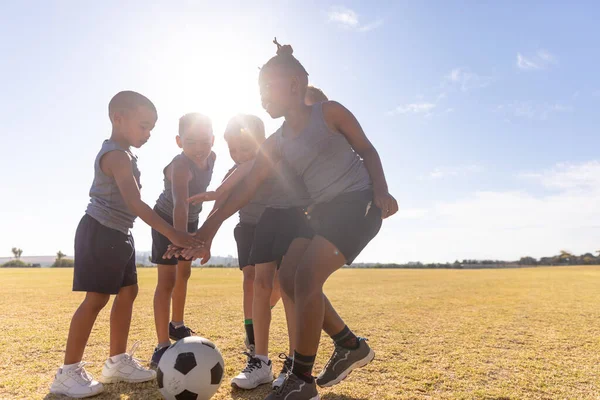 晴れた日には野球場でサッカーボールを手にした多人種の小学生たち 子供時代教育スポーツトレーニングバックライトチームスポーツスポーツ活動のコンセプト — ストック写真