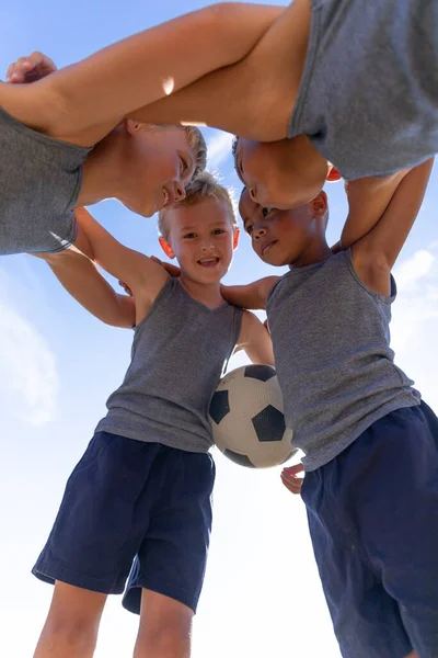 サッカーをしながらハドルを作る多人種の小学生の低角度ビュー 変化のない子供時代教育スポーツトレーニングチームスポーツ活動のコンセプト — ストック写真