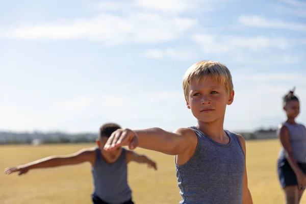 晴れた日の空に腕を伸ばして運動をする白人の小学生 変化のない子供時代教育スポーツトレーニングヨガ身体教育の概念 — ストック写真