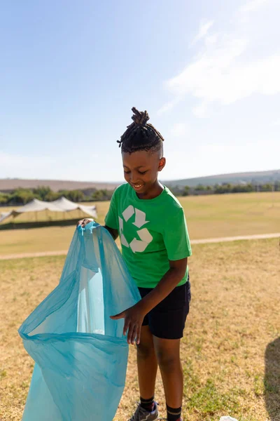 アフリカ系アメリカ人の小学生がごみ袋にプラスチックを集めて空に微笑んだ 変化のない持続可能なライフスタイル教育清掃責任リサイクルの概念 — ストック写真