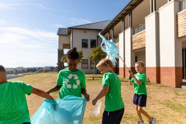 Multiracial Elementary Schoolboys Cleaning Ground School Building Sunny Day Unaltered — Stock Photo, Image