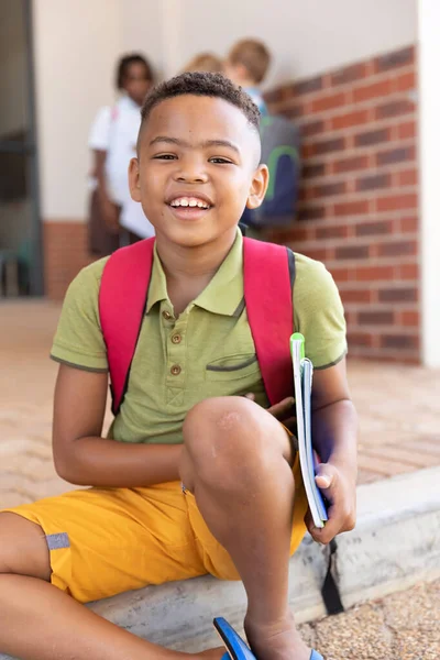Portret Van Een Glimlachende Biraciale Basisschooljongen Met Boeken Vloer School — Stockfoto