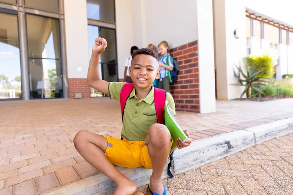 Retrato Sonriente Colegial Birracial Con Mano Levantada Sentada Suelo Escuela — Foto de Stock