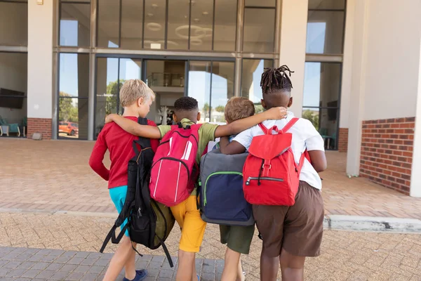 Bakifrån Multiracial Grundskolebarn Med Ryggsäck Och Arm Runt Stående Campus — Stockfoto