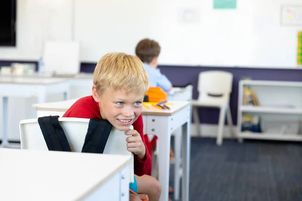 Lachende Blanke Basisschooljongen Die Wegkijkt Terwijl Hij Stoel Leunt Klas — Stockfoto