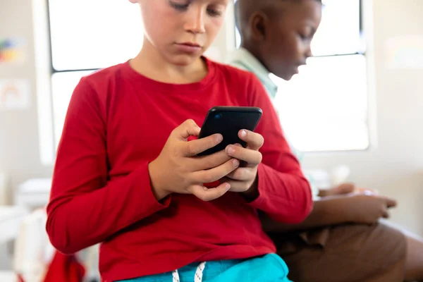 Multiraciala Skolpojkar Som Använder Smartphone När Sitter Vid Skrivbordet Klassrummet — Stockfoto