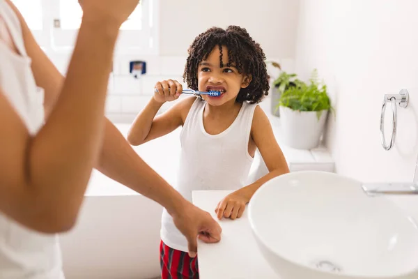 Niño Hispano Cepillándose Los Dientes Mientras Mira Padre Parado Junto —  Fotos de Stock