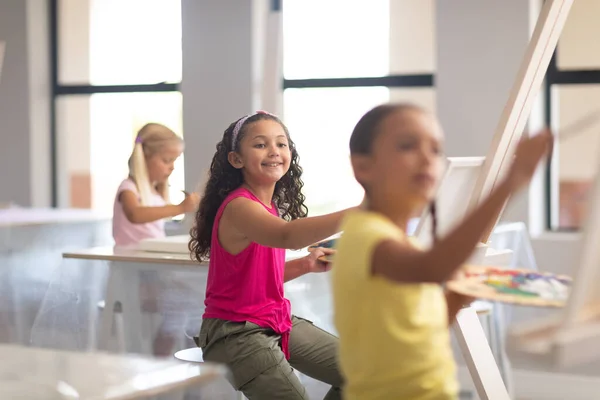 Lächelnde Grundschülerinnen Malen Während Des Zeichenunterrichts Der Schule Auf Staffelei — Stockfoto