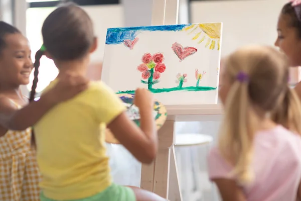 Happy Multiracial Elementary Schoolgirls Standing Caucasian Girl Painting Easel Class — Stock Photo, Image