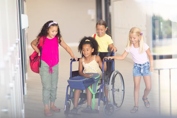 Усміхнені Багаторасові Початкові Школярки Допомагають Жінці Однокласниці Сидіти Інвалідному Кріслі — стокове фото