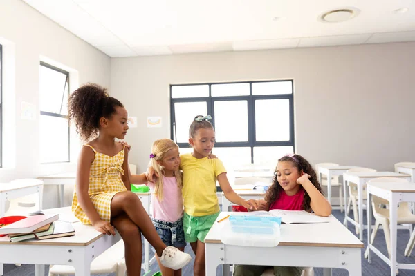 Multiraciala Grundläggande Skolflickor Tittar Kvinnliga Klasskamrat Läsa Bok Vid Skrivbordet — Stockfoto