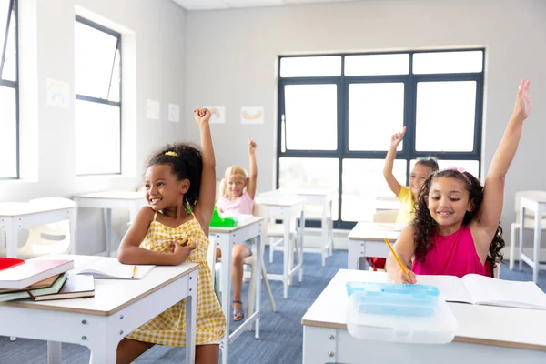 学校の授業中に机に座りながら手を挙げている元気な小学生たち 変化のない子供時代教育知性を学校のコンセプトに — ストック写真