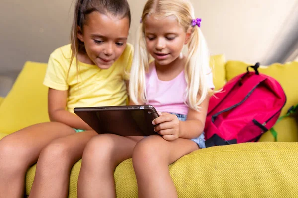 Escolares Primaria Caucásicas Sonrientes Mirando Tableta Digital Mientras Están Sentadas —  Fotos de Stock