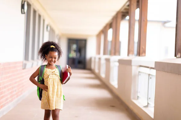 Smiling Multiracial Elementary Schoolgirl Books Backpack Standing Corridor Unaltered Childhood — Stock Photo, Image