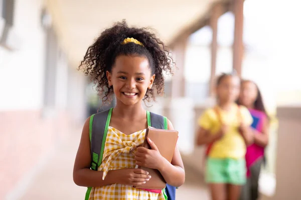 Portrait Smiling Biracial Elementary Schoolgirl Holding Books While Standing Corridor — Stock Photo, Image