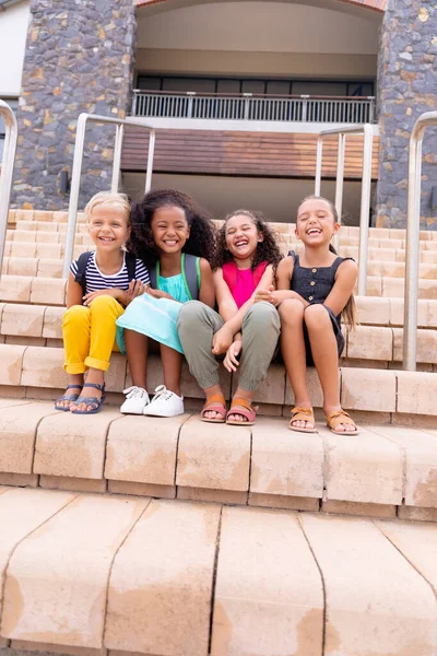 Full Length Multiracial Cheerful Elementary Schoolgirls Sitting Steps School Building — Stock Photo, Image