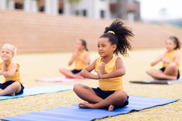 Multiraciale Basisschoolmeisjes Met Handen Geklemd Zittend Een Yogamat School Ongewijzigd — Stockfoto