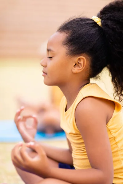 Sidovy Biracial Grundskoleflicka Med Slutna Ögon Meditera Medan Sitter Marken — Stockfoto