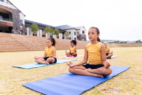 Multirassische Grundschülerinnen Meditieren Während Sie Auf Der Turnmatte Auf Dem — Stockfoto