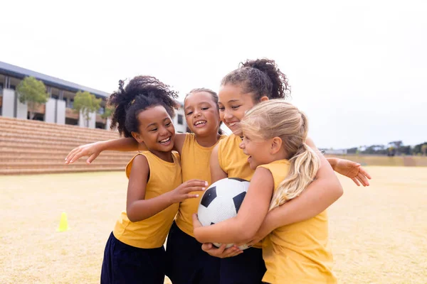 Glada Multiracial Grundskola Flickor Med Fotboll Omfamning När Står Marken — Stockfoto