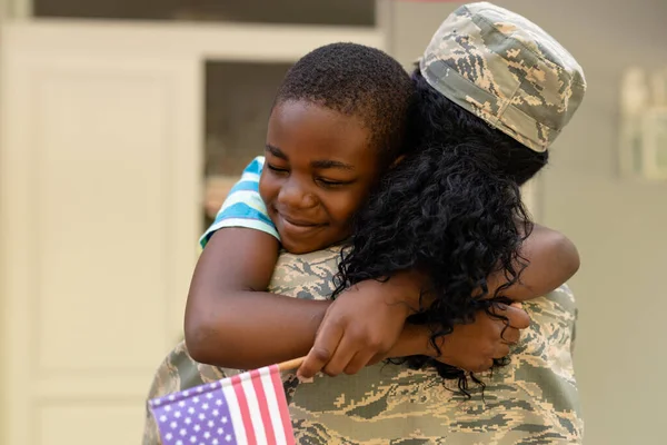 非洲裔美国男孩到家时抱着士兵母亲 不变的 自豪的 军队的 美国国旗的 到达的 团聚的 归国的 武装部队的和爱国主义的 — 图库照片